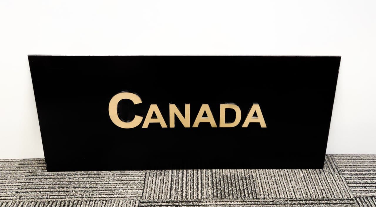 Black sign with raised gold letters reading Canada